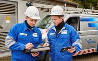 Zwei Techniker in Blaumännern betrachten Tablets vor einem Technikfahrzeug Zwei Techniker in Blaumännern betrachten Tablets vor einem Technikfahrzeug