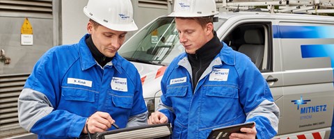 Zwei Techniker in Blaumännern betrachten Tablets vor einem Technikfahrzeug Zwei Techniker in Blaumännern betrachten Tablets vor einem Technikfahrzeug