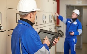 Techniker mit portablem Eingabegerät steht mit Kollegen vor einer Anlage Techniker mit portablem Eingabegerät steht mit Kollegen vor einer Anlage