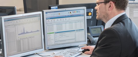 Mitarbeiter am Schreibtisch vor zwei Monitoren arbeitet am Rechner Mitarbeiter am Schreibtisch vor zwei Monitoren arbeitet am Rechner