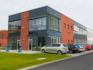 Gebäude mit Fassade in grau und orange mit Parkplätzen - Außenaufnahme Gebäude mit Fassade in grau und orange mit Parkplätzen - Außenaufnahme