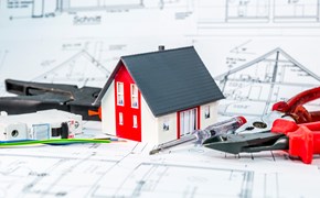 Kleines Hausmodell und Werkzeug auf einem Bauplan Kleines Hausmodell und Werkzeug auf einem Bauplan