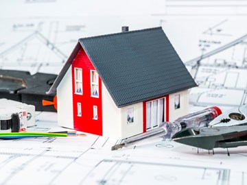 Kleines Hausmodell und Werkzeug auf einem Bauplan Kleines Hausmodell und Werkzeug auf einem Bauplan