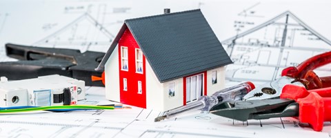 Kleines Hausmodell und Werkzeug auf einem Bauplan Kleines Hausmodell und Werkzeug auf einem Bauplan