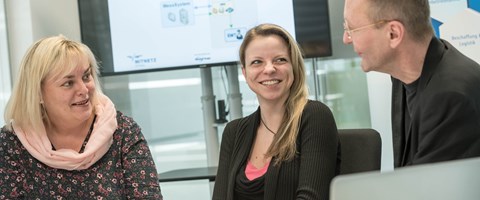 Ein Mann und zwei Frauen, an einem Tisch im Konferenzraum sitzend, im Gespräch Ein Mann und zwei Frauen, an einem Tisch im Konferenzraum sitzend, im Gespräch