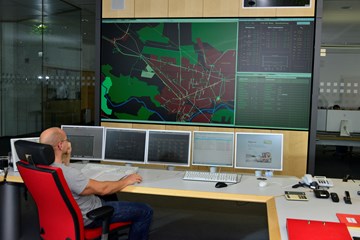 Mitarbeiter auf einem roten Stuhl vor Monitoren der Schaltleitung Mitarbeiter auf einem roten Stuhl vor Monitoren der Schaltleitung
