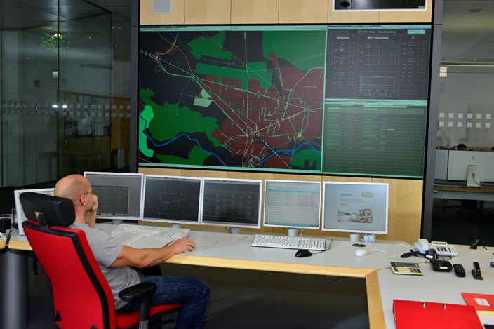 Mitarbeiter auf einem roten Stuhl vor Monitoren der Schaltleitung Mitarbeiter auf einem roten Stuhl vor Monitoren der Schaltleitung