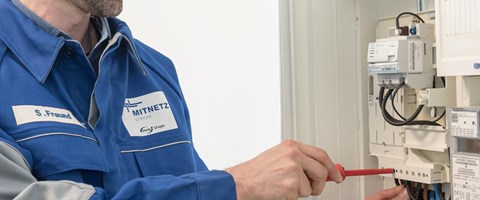 Mitarbeiter mit rotem Schraubenzieher arbeitet an einem Stromzähler Mitarbeiter mit rotem Schraubenzieher arbeitet an einem Stromzähler