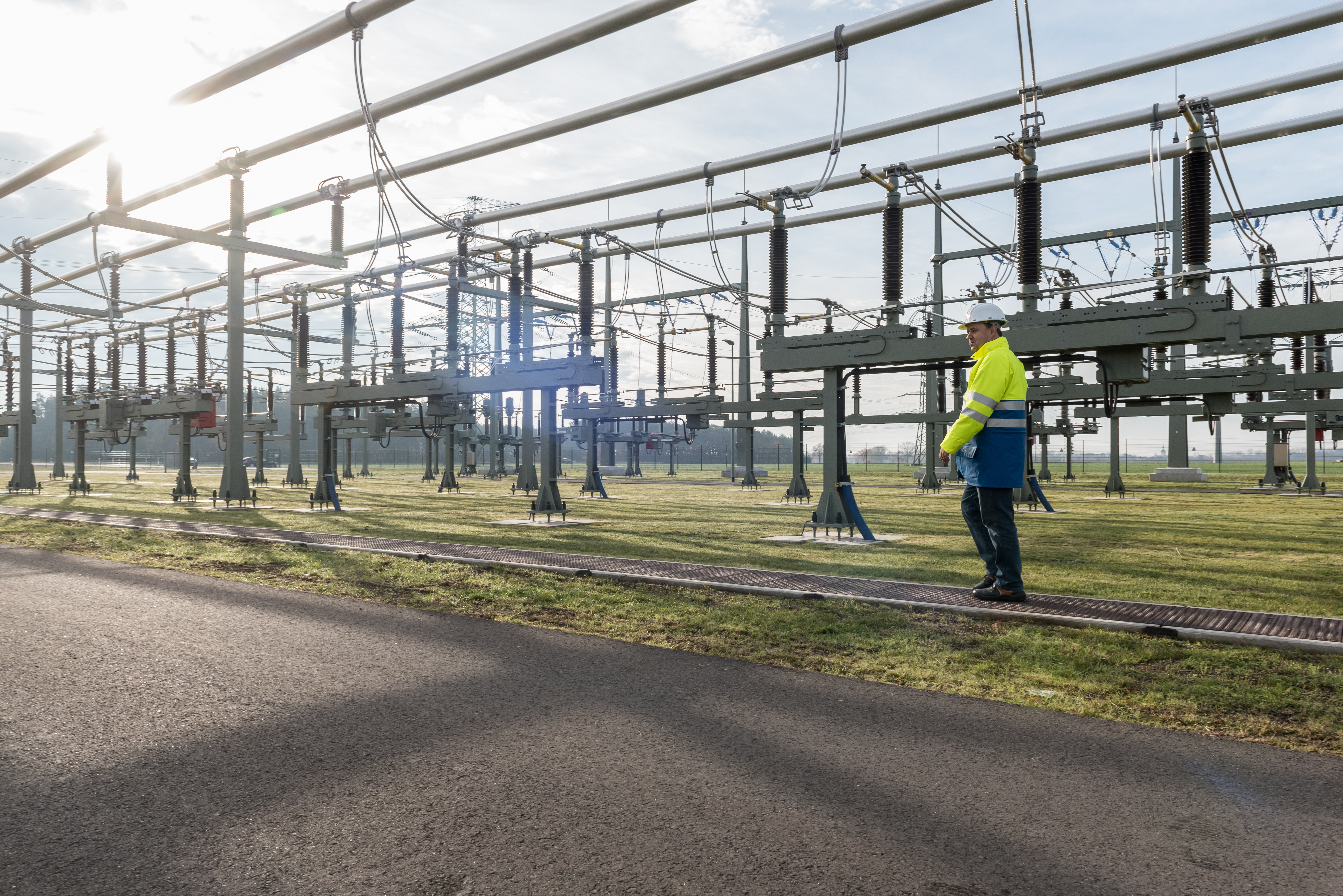 Mitarbeiter mit Helm und Warnschutzjacke bei Anlagen im Umspannwerk