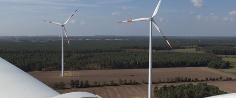Sicht vom Kopf eines Windrads auf ein Feld mit zwei weiteren Windrädern Sicht vom Kopf eines Windrads auf ein Feld mit zwei weiteren Windrädern